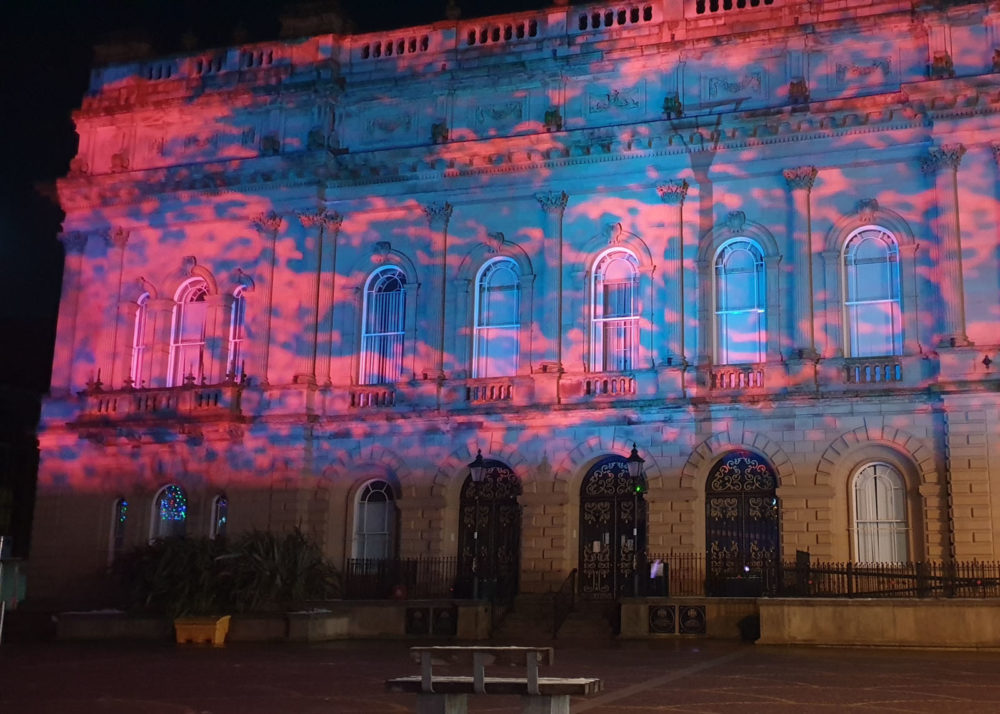 A large building lit up by coloured projections